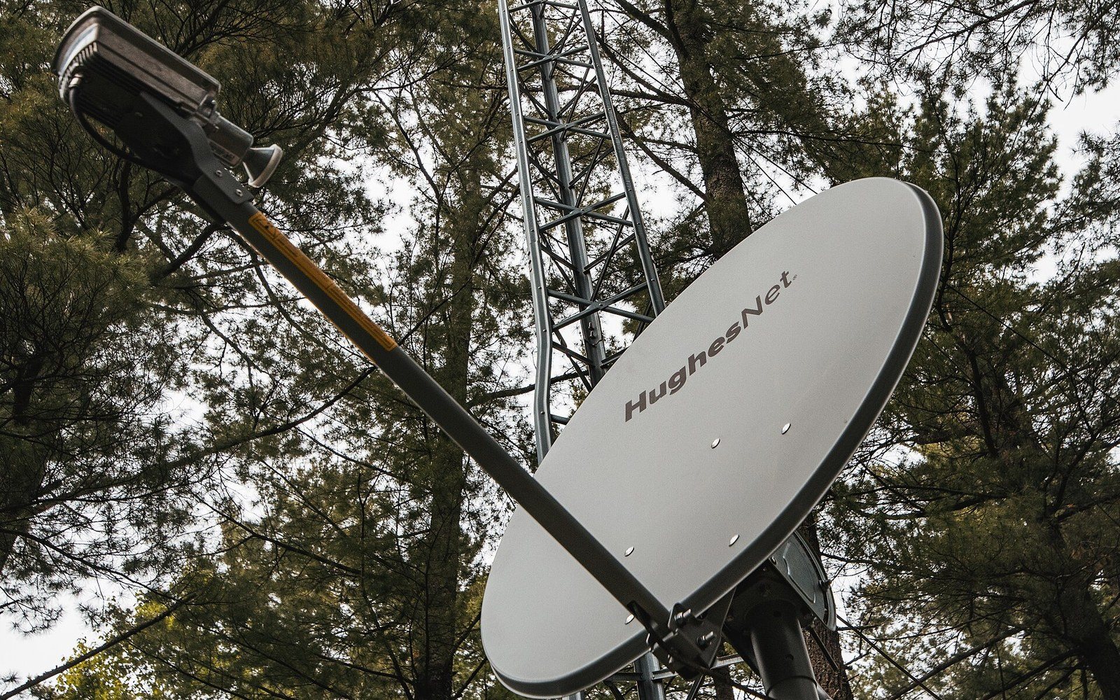 A satellite internet dish mounted beside a mast at a rural property