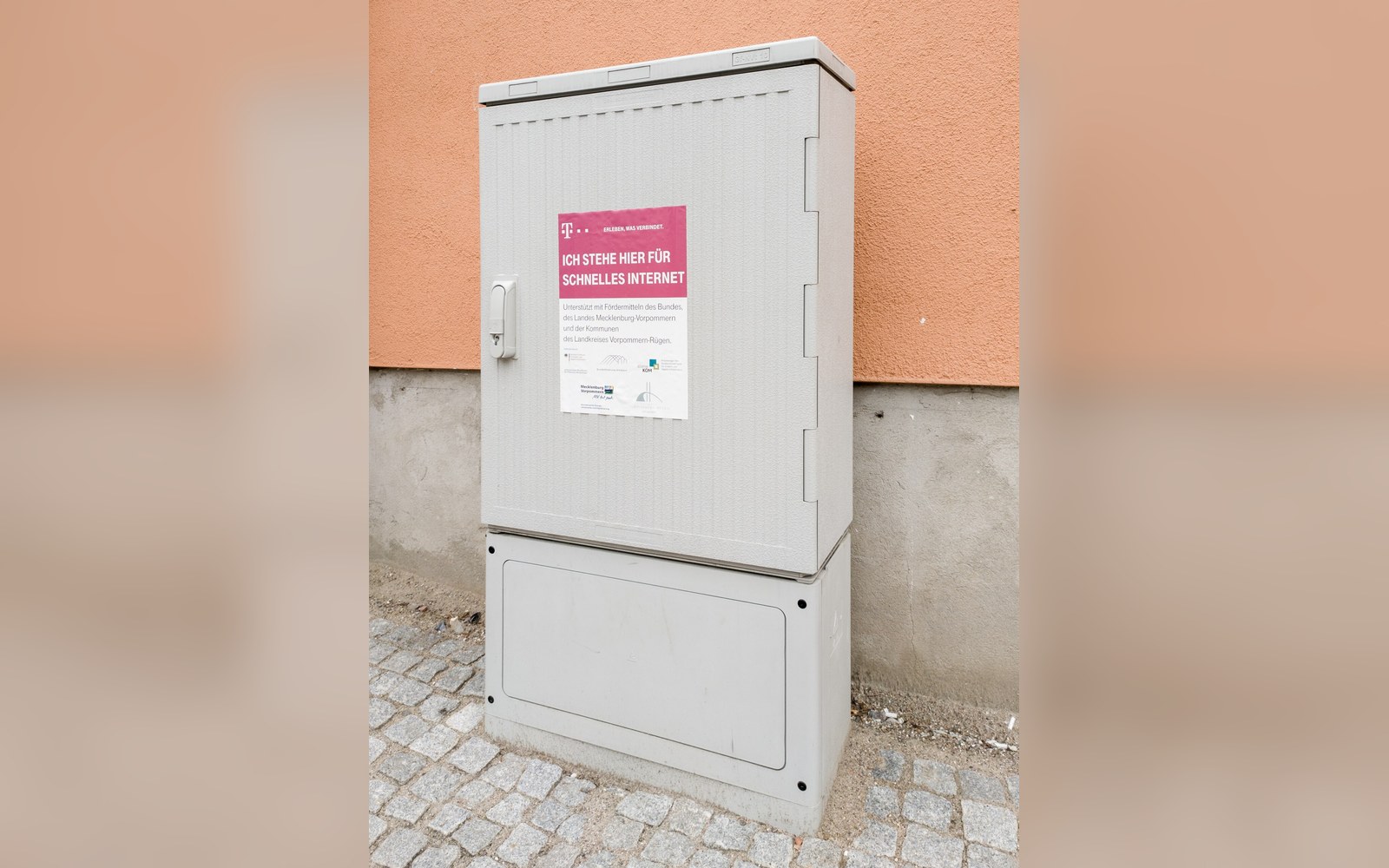 A kerbside pedestal cabinet standing open with fibre trays inside, flat daylight